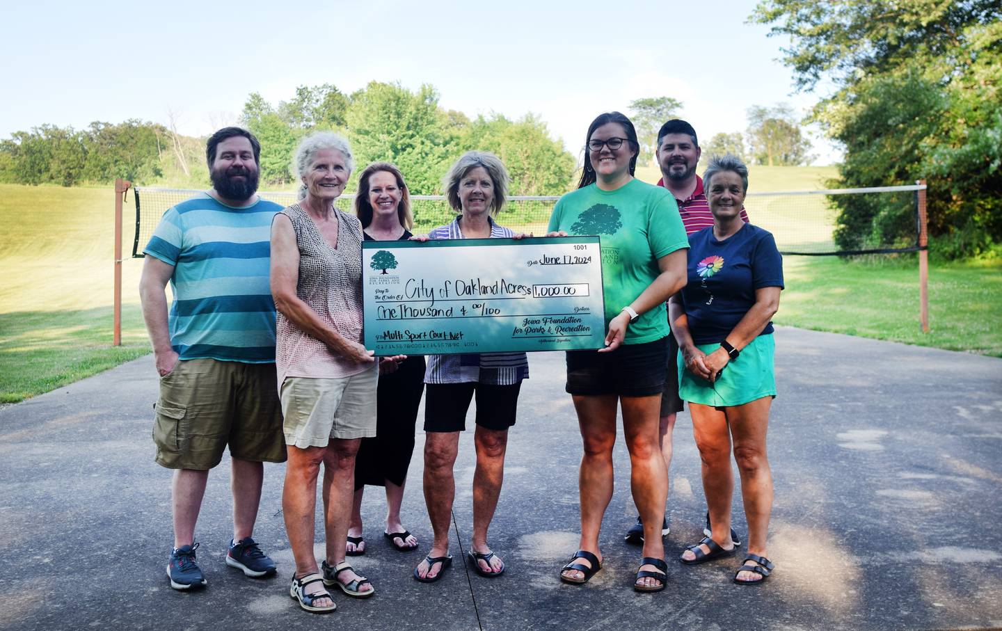 From left: Clinton Follette, Susan Martin, Cassy Thompson, Lisa Griffith, Danae Edwards, Jared Johnston and Tammy Strawser pose for a picture with a $1,000 check from the Iowa Foundation for Parks and Recreation to go towards an adjustable net system for the city park in Oakland Acres.