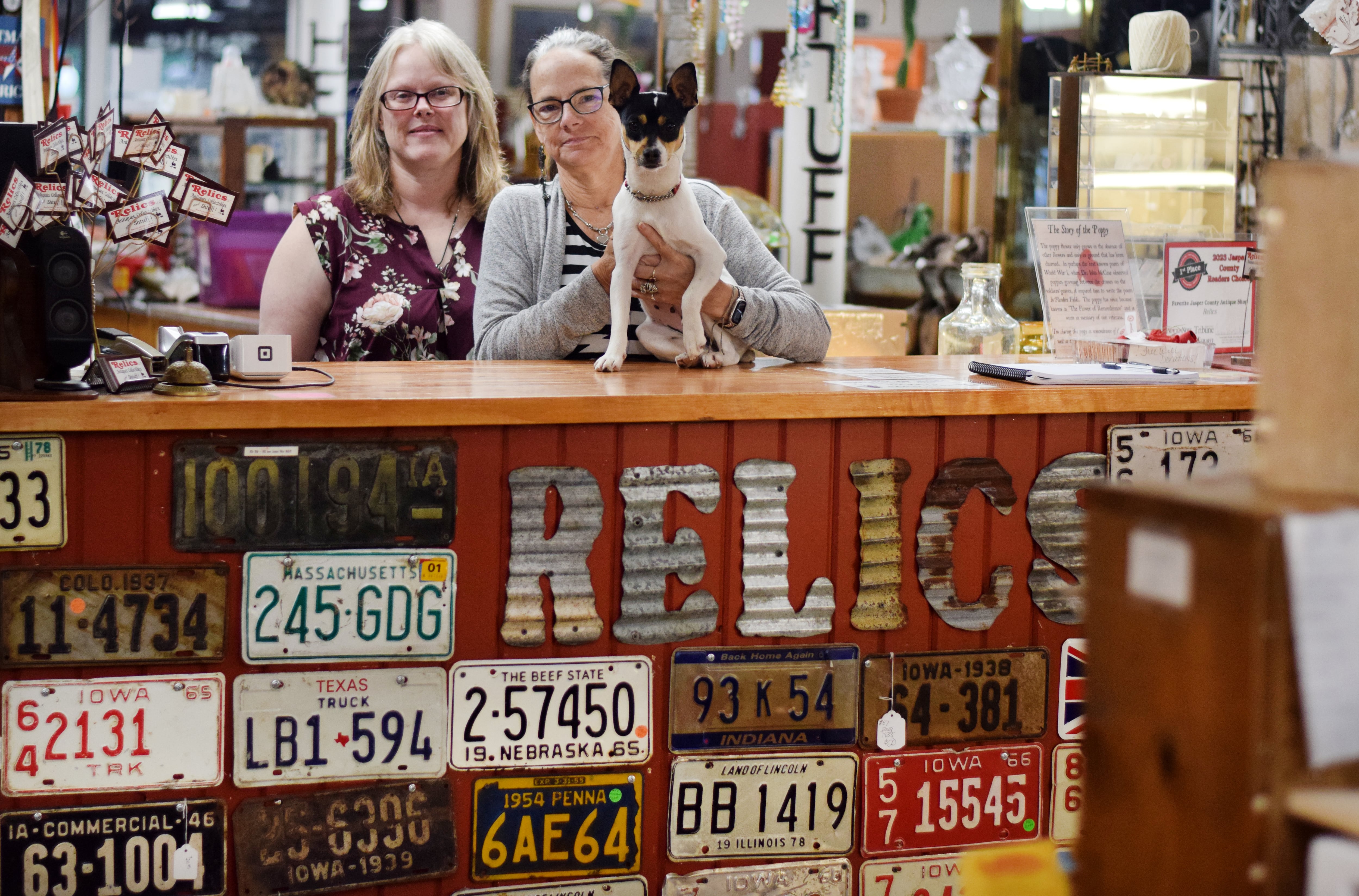 Carrie Putz, Laurie Nelson and Pickle pose for a picture at the front desk of Relics, LLC, an antique shop in downtown Newton that announced it will be closing by the end of the year.