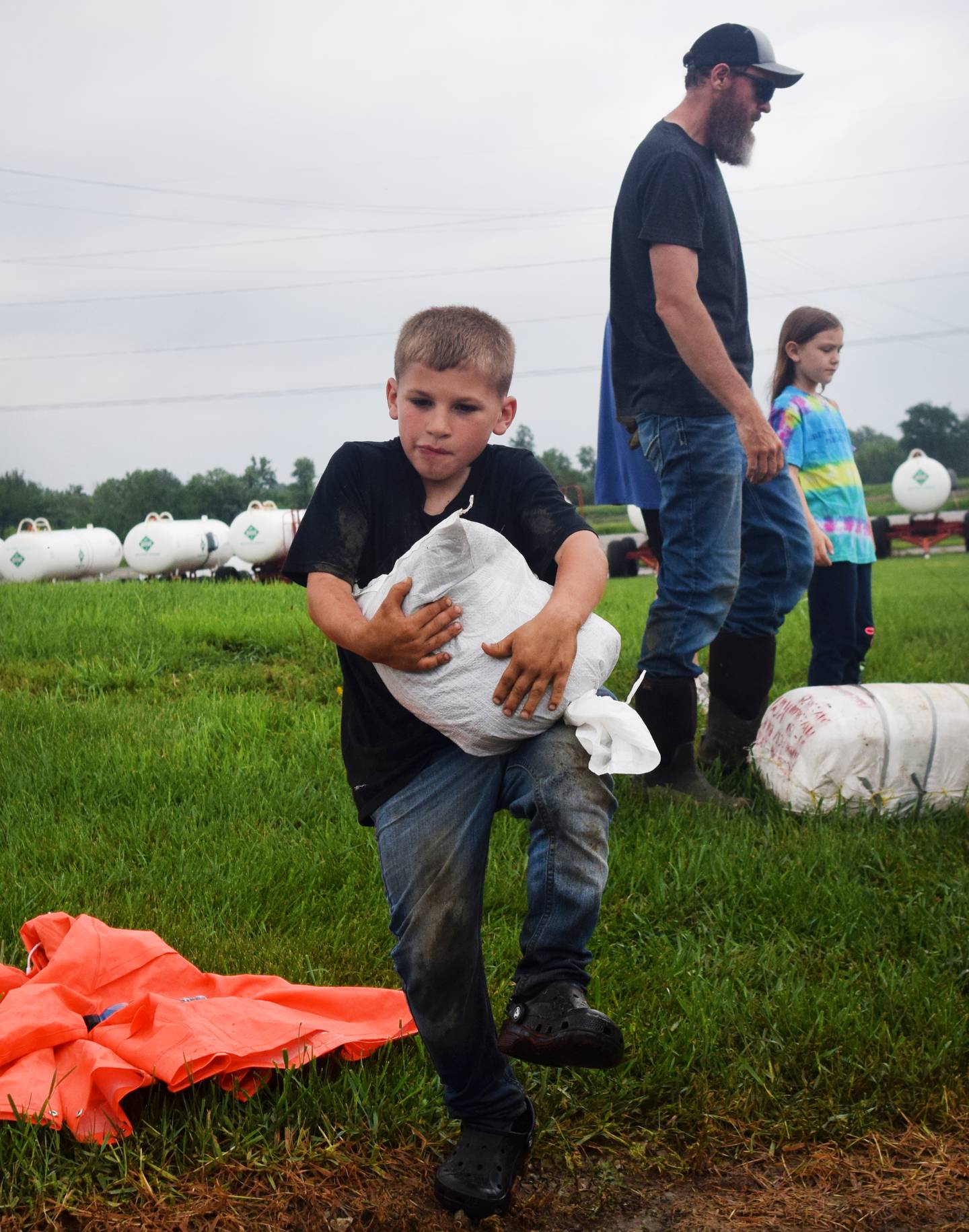 Trigg Dhondt, 7, of Kellogg on May 21 carries a sandbag alongside volunteers preparing for even more flooding in the community. Kellogg was hit hard by floods, with the waters reaching as far as the Country Store and overtaking Highway 224 and a housing development after a culvert got clogged.