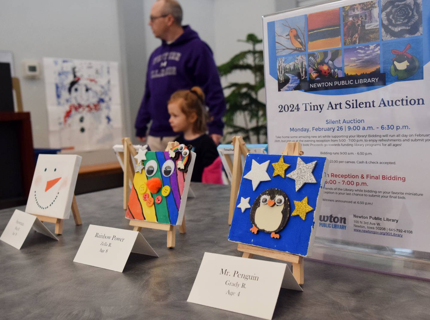 Library patrons walk past the tiny art canvases on display at the Newton Public Library. The Tiny Art Show celebrated its third year and its second auction this winter.